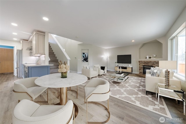 dining area with baseboards, stairway, recessed lighting, light wood-style flooring, and a fireplace