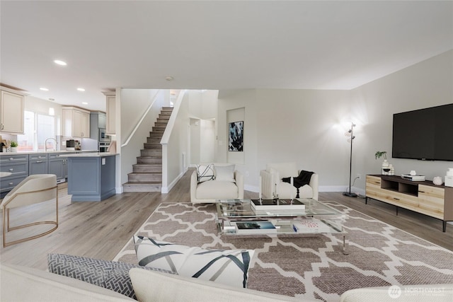 living area featuring stairway, recessed lighting, baseboards, and light wood-style floors