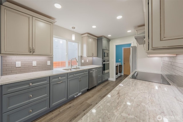 kitchen with washer / clothes dryer, a sink, gray cabinetry, stainless steel appliances, and light wood-style floors