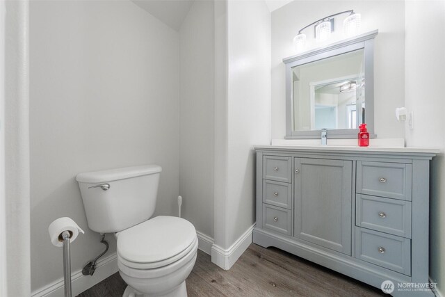 bathroom with vanity, toilet, wood finished floors, and baseboards