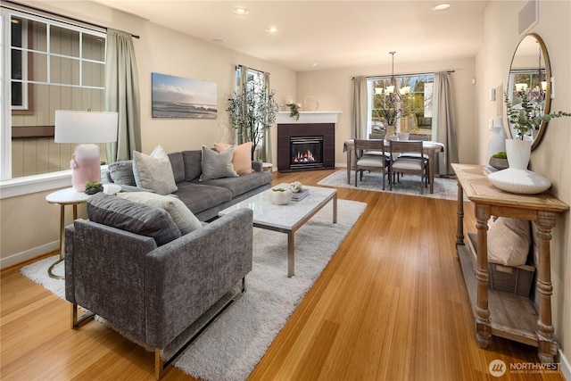 living room featuring a chandelier, baseboards, light wood-style flooring, and recessed lighting