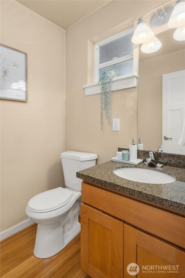 bathroom with toilet, baseboards, wood finished floors, and vanity