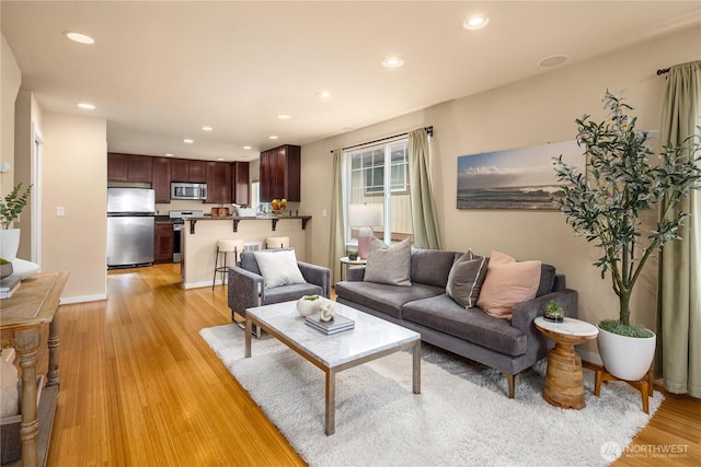 living area with baseboards, recessed lighting, and light wood-style floors