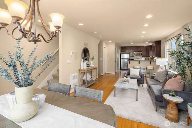 living room featuring stairs, light wood-type flooring, and recessed lighting