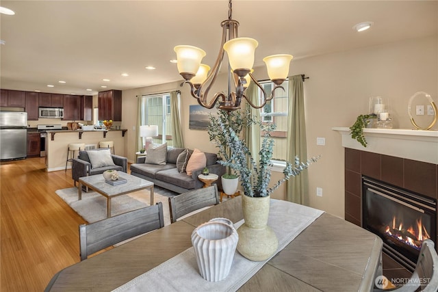 dining room with recessed lighting, a tile fireplace, and light wood-style floors