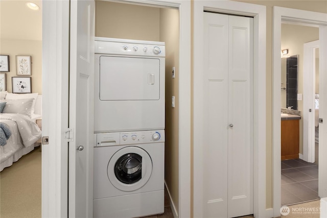 washroom featuring stacked washing maching and dryer and tile patterned floors