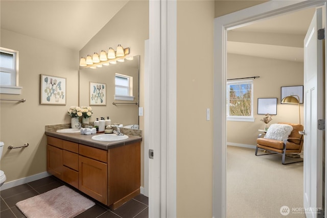 bathroom with toilet, plenty of natural light, vaulted ceiling, and a sink