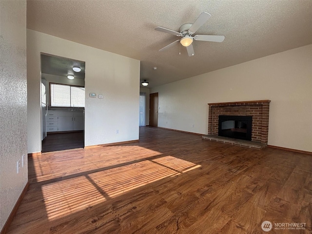 unfurnished living room with baseboards, wood finished floors, a ceiling fan, and a textured ceiling