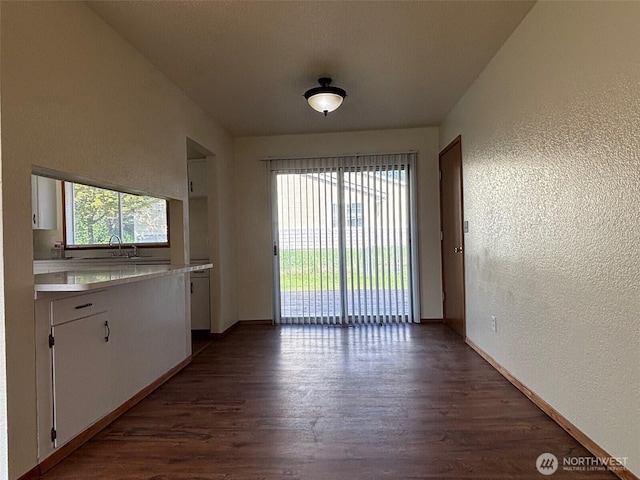 interior space featuring dark wood-style floors, baseboards, and a textured wall