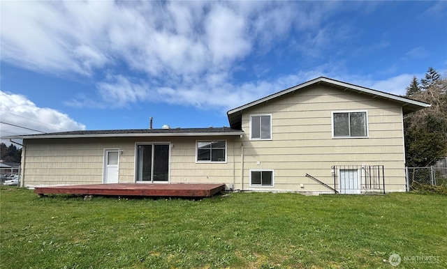 rear view of property featuring a deck, fence, and a yard