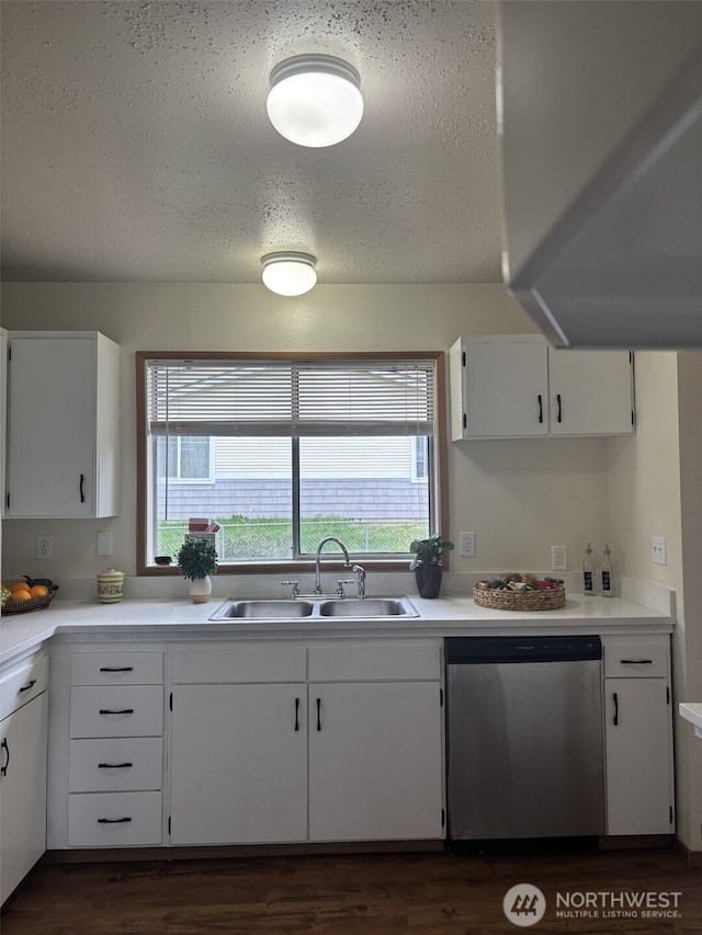 kitchen featuring white cabinetry, stainless steel dishwasher, a textured ceiling, and a sink