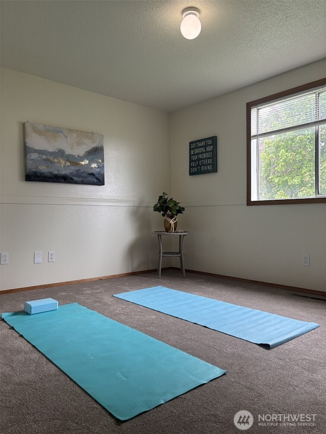 workout room featuring carpet floors and a textured ceiling