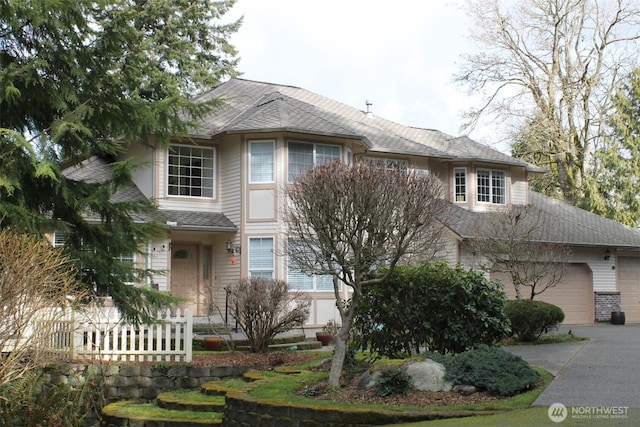 view of front of home featuring driveway, a shingled roof, and an attached garage