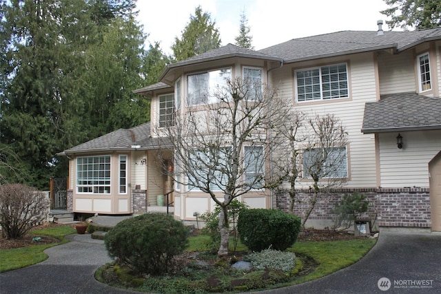 view of front facade with brick siding and a shingled roof