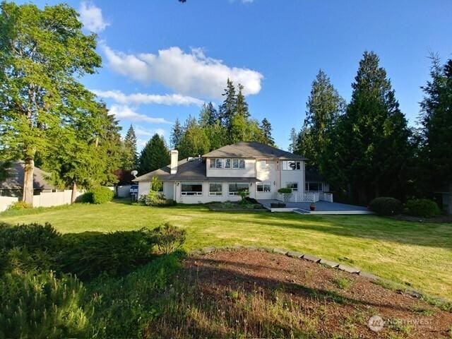 rear view of property featuring a lawn, a chimney, and fence