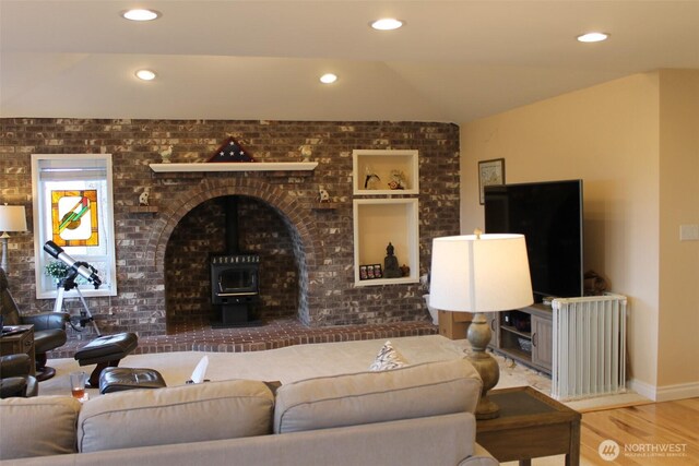 living area featuring recessed lighting, a wood stove, brick wall, and wood finished floors