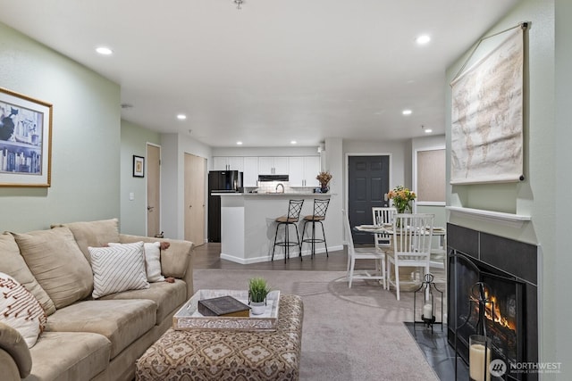 living room featuring recessed lighting, baseboards, and a fireplace with flush hearth