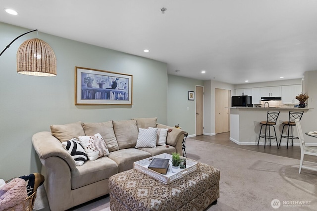 living room featuring recessed lighting, baseboards, and light carpet