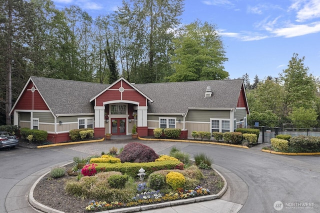 view of front of property with french doors, fence, and roof with shingles