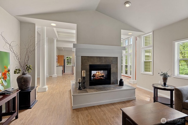 living room with a fireplace, decorative columns, and light wood-style floors