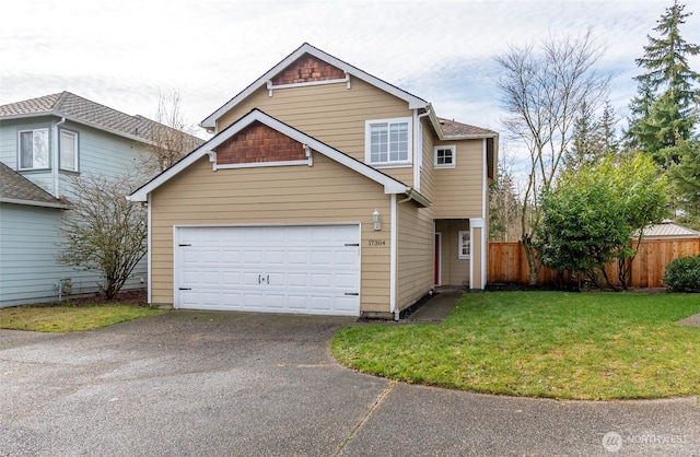 traditional-style home with a garage, fence, and a front lawn