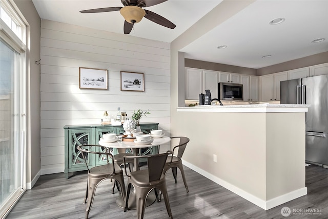 dining space featuring light wood finished floors, ceiling fan, and baseboards