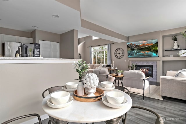 dining area with built in shelves, wood finished floors, and a glass covered fireplace