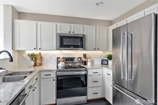 kitchen with backsplash, white cabinetry, stainless steel appliances, and a sink