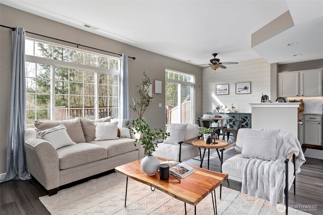 living room with wood finished floors, visible vents, and a ceiling fan