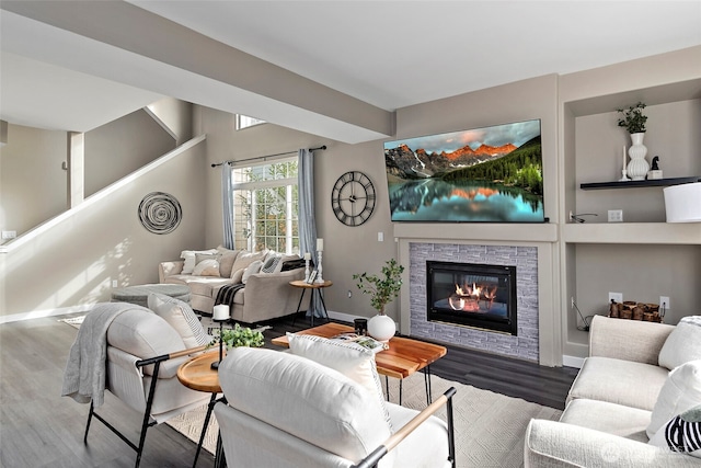 living area featuring a glass covered fireplace, wood finished floors, and baseboards