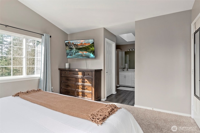 bedroom with lofted ceiling, a sink, baseboards, and ensuite bathroom