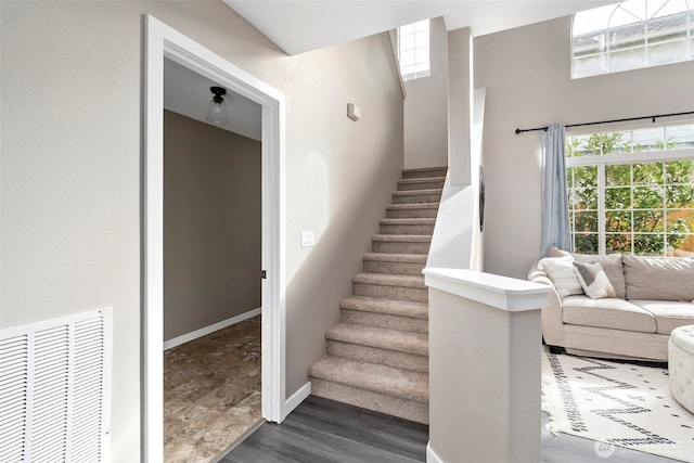 stairway with visible vents, baseboards, and wood finished floors