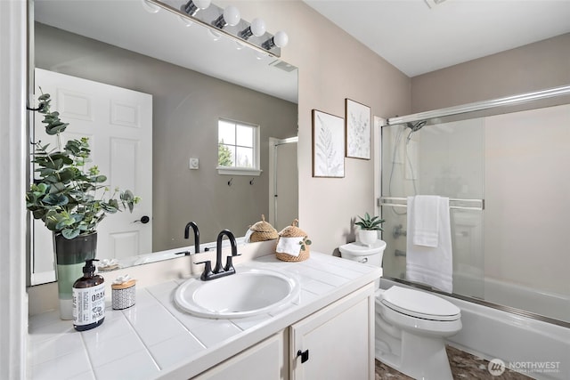 bathroom with visible vents, bath / shower combo with glass door, vanity, and toilet