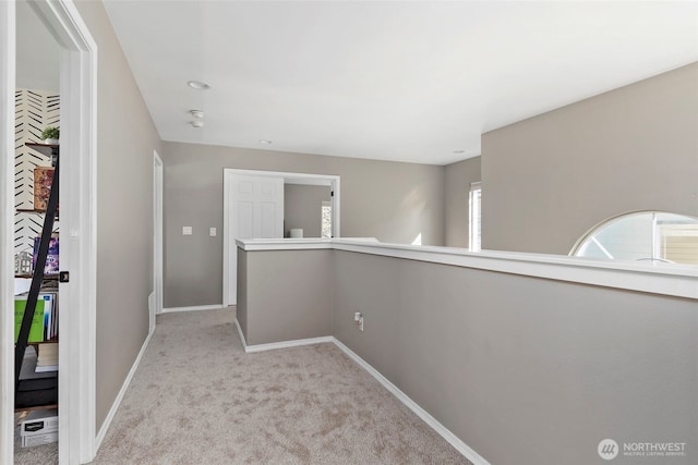 hall with light colored carpet and baseboards