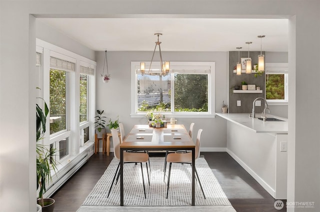 dining space with a baseboard heating unit, a chandelier, dark wood finished floors, and baseboards