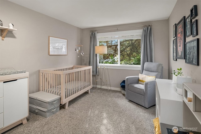 carpeted bedroom featuring a nursery area and baseboards