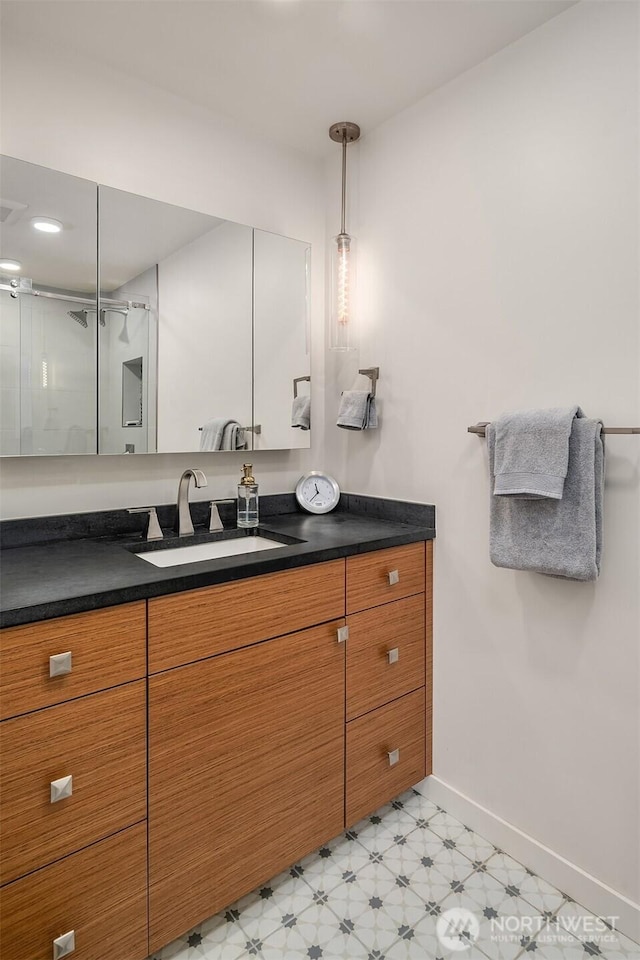 bathroom featuring a stall shower, vanity, baseboards, and tile patterned floors