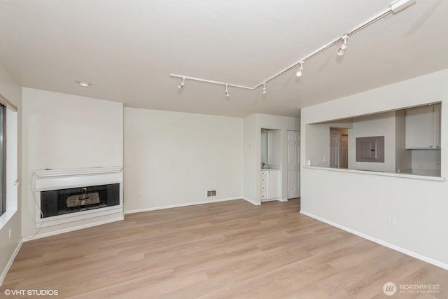 1221 Harbor Ave SW Unit 105, Seattle, WA 98116 - unfurnished living room featuring track lighting, light wood-type flooring, a fireplace, and baseboards