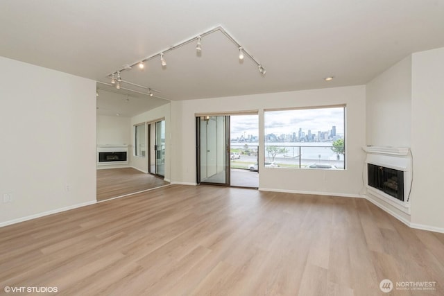 1221 Harbor Ave SW Unit 105, Seattle, WA 98116 - unfurnished living room featuring a fireplace, track lighting, baseboards, and light wood finished floors