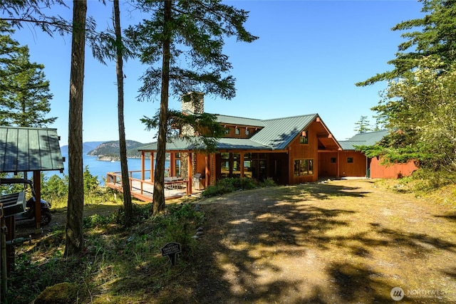 exterior space with a chimney, a water view, and metal roof