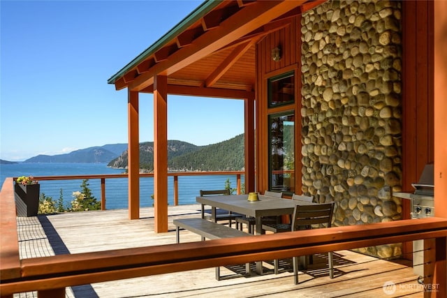 deck featuring outdoor dining space and a water and mountain view