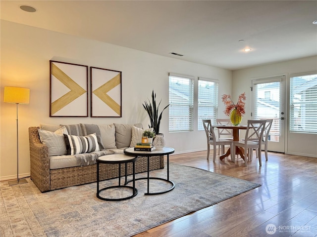 living area featuring visible vents, baseboards, and wood finished floors