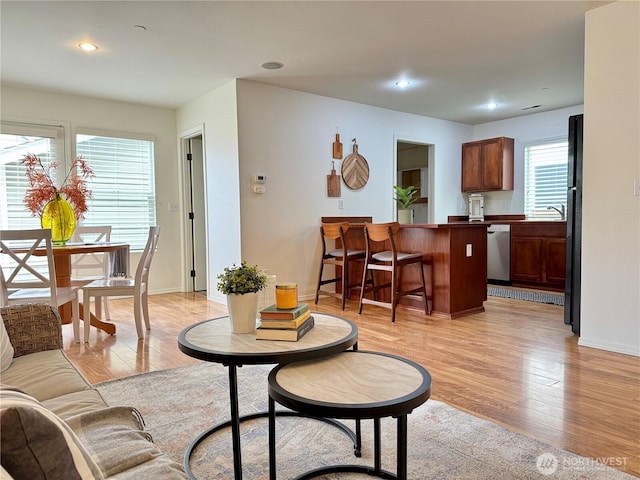 living area featuring recessed lighting, baseboards, and light wood-type flooring