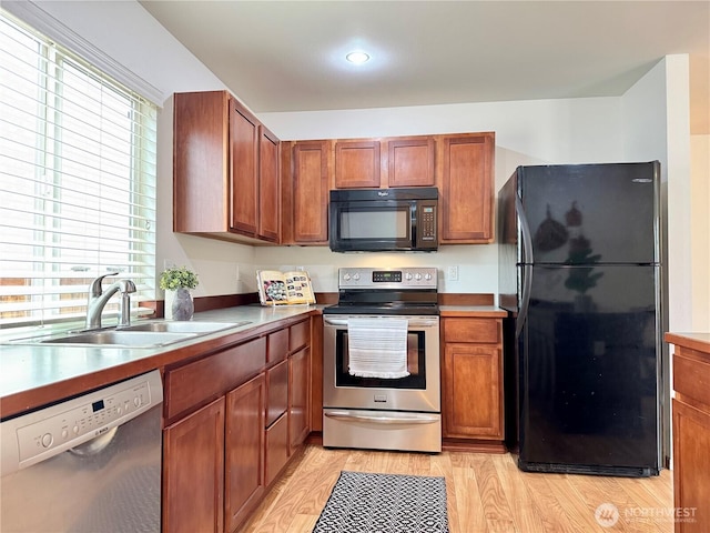 kitchen featuring brown cabinets, black appliances, light wood-style floors, and a sink