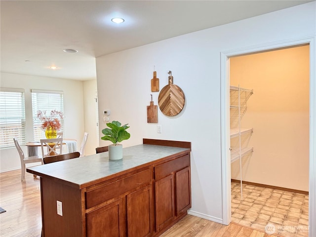 kitchen with brown cabinets, light wood-style flooring, and baseboards