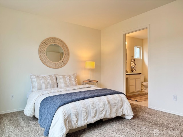 carpeted bedroom with connected bathroom and baseboards