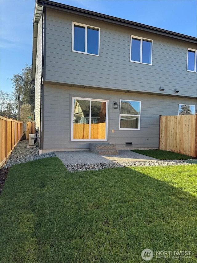 back of house featuring a yard, a patio, and a fenced backyard