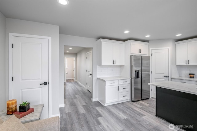 kitchen with white cabinets, stainless steel fridge, light wood-style flooring, and recessed lighting