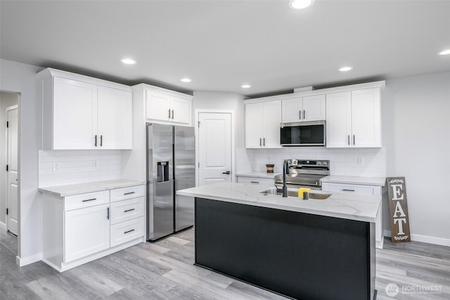 kitchen with light wood-type flooring, white cabinetry, appliances with stainless steel finishes, and a sink