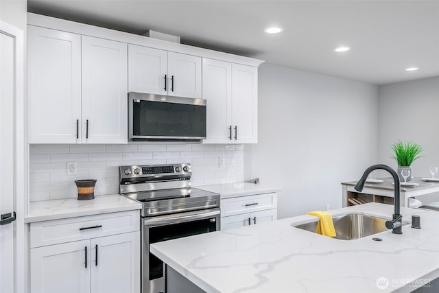 kitchen featuring appliances with stainless steel finishes, a sink, white cabinetry, and tasteful backsplash